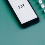 Telemóvel com a palavra PAY no ecrã, sobre fundo verde