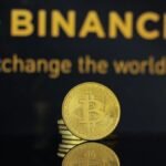 Logótipo da Binance e moedas de bitcoin